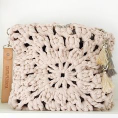 a crocheted purse with tassels and a leather tag