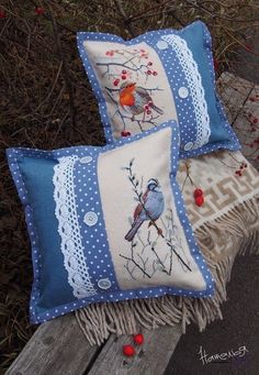 two decorative pillows sitting on top of a wooden bench