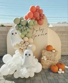 there are balloons and ghost decorations on the street corner with pumpkins in the foreground