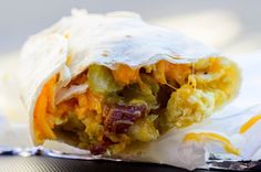 a burrito filled with lots of toppings on top of a piece of tin foil