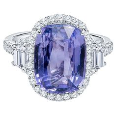 This beautiful cocktail ring features a 5.68 cushion cut natural violet sapphire accented by 0.55 carat total weight in round diamonds and 0.34 carat total weight in two step cut trapezoid diamonds. The cocktail ring is set in platinum and is currently a size 6 but can be resized upon request. This sapphire and diamond cocktail ring can be worn everyday or saved for special occasions. Measurements: Sapphire measures 12.25 x 9.18 x 5.10mm Report: Report: Reunigem FK58560314 Luxury Purple Sapphire Ring For Wedding, Luxury Classic Amethyst Cushion Cut Ring, Formal Purple Sapphire Rings, Purple Brilliant Cushion Cut Rings, Purple Cushion Cut Brilliant Ring, Gia Certified Cushion Cut Tanzanite Ring, Gia Certified Tanzanite Cushion Cut Ring, Purple Cushion Cut Diamond Rings, Purple Diamond Cushion Cut Rings