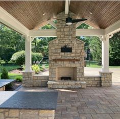 an outdoor patio with stone fireplace and seating