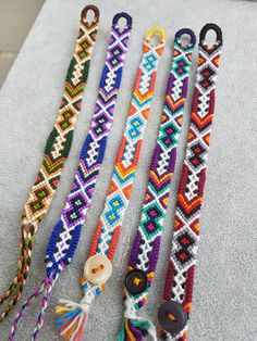 four different bracelets with tassels and buttons on them sitting on the floor