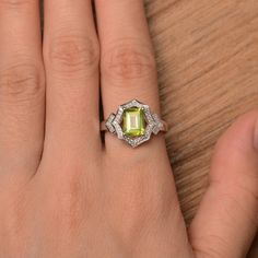 a woman's hand with a ring on it that has a green stone in the middle