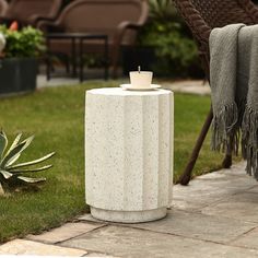 a white table sitting on top of a grass covered ground next to a chair and potted plant