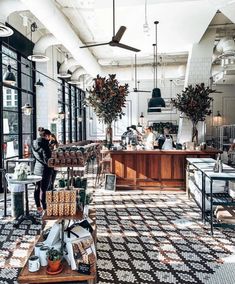 the interior of a coffee shop with lots of counter space and plants in pots hanging from the ceiling