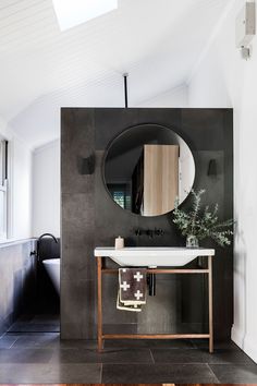 a black and white bathroom with a round mirror