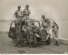 an old black and white photo of men in uniforms standing on the back of a truck