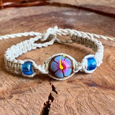 Get into the chill zone with our Handmade Blue Hawaiian Hibiscus Flower Hemp Bracelet or Anklet, featuring a hand-painted wood bead and matching glass beads. It's all about that laid-back Boho Hippie Hawaiian vibe you crave. Perfect for anyone who digs a retro, relaxed feel. Whether you're a guy or a girl who loves the surf life, this versatile hemp jewelry piece is for you. Who is it for? : Anyone! Hemp Jewelry is ageless and timeless and has no gender boundaries! What is it made of? : 100% natural hemp twine featuring a combo of twist & square knotting & hand painted blue hibiscus flowers on wood beads and iridescent glass crow beads and matching brown wood beads. Choose your custom hemp color below or choose as shown! Custom Options: 1. Choose your custom size from the drop menu. 2. Cho Adjustable Hippie Flower Jewelry, Adjustable Hand Painted Blue Bracelet, Adjustable Blue Hand Painted Bracelet, Adjustable Blue Hand Painted Bracelets, Adjustable Flower-shaped Bohemian Beaded Bracelets, Hand Painted Adjustable Jewelry For Festivals, Hippie Skater Style, Crochet Slouchy Hat, Chill Zone