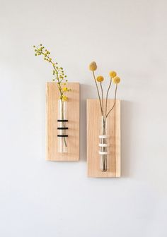 two vases with flowers in them are on the wall, one is made out of wood