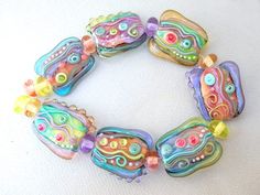 a colorful bracelet made with glass beads on a white tablecloth, decorated with multicolored swirls