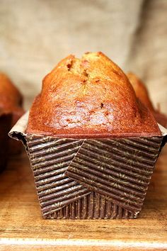 a muffin sitting on top of a wooden table next to two other oranges