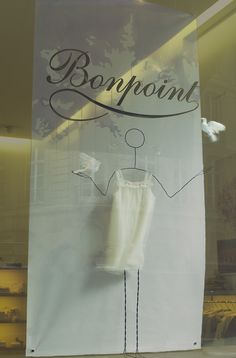 a window display with an advertisement for a clothing store in the front and behind it is a mannequin's torso