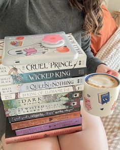 a woman is holding a stack of books and a cup of coffee