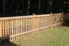 a wooden fence in front of some trees