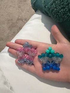 a person's hand holding several small pieces of glass bead jewelry on their palm