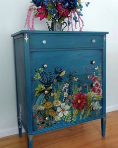 a blue cabinet with flowers and butterflies painted on it