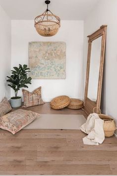 a room with a large mirror and some pillows on the floor next to a potted plant