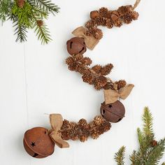 pine cones and acorns are arranged on a white surface with evergreen branches, pine cones, and twine of twine