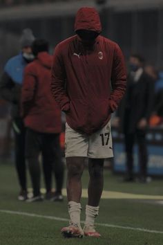 a man standing on top of a soccer field wearing a red jacket and white shorts