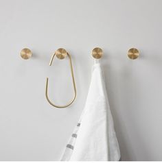 three brass hooks hang on the wall next to a towel