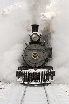 an old fashioned steam train traveling through the snow