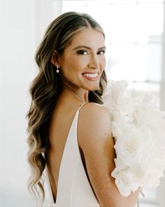 a beautiful woman in a white dress holding flowers