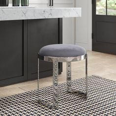 a round stool sits in the middle of a kitchen with an area rug on the floor