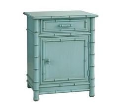 a small blue cabinet with an open door and bamboo decoration on the front, sitting against a white background