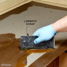 a person in blue gloves and white gloves is applying laminate to the top of a wooden table