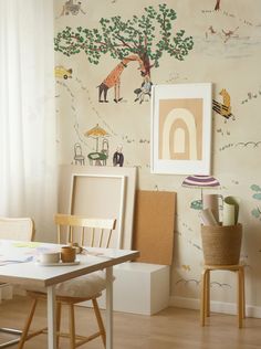 a table and chairs in a room with wall paper on the walls, paintings above them