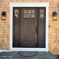 the front door of a house with two lights on it