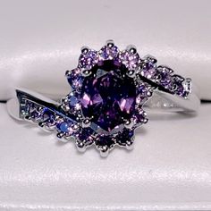 a fancy ring with an amethyst purple stone surrounded by white and blue diamonds