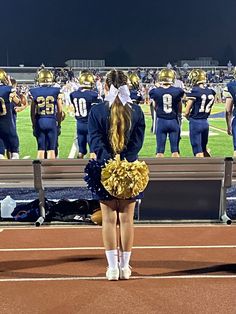 a cheerleader stands on the sidelines at a football game