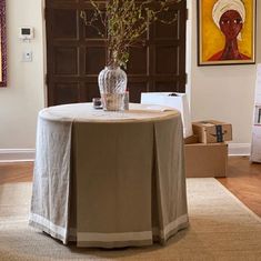 a table with a vase on it in the middle of a room filled with paintings