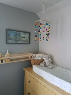 a baby's room with a crib, changing table and hanging mobile in the corner