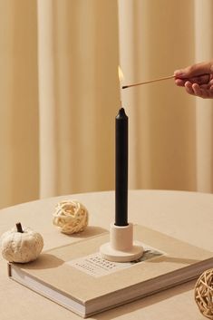 a person lighting a candle on top of a book