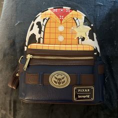 This Disney Loungefly Toy Story Woody Western Vegan Leather Mini Backpack Is A Must-Have For Any Fan Of The Franchise. With Its Stylish Design And Functional Size, It's Perfect For Carrying All Your Essentials On The Go. The Backpack Features Woody, The Beloved Character From The Movie, And Is Made From High-Quality Vegan Leather For A Durable And Long-Lasting Design. The Backpack Is Perfect For Collectors And Fans Of All Ages, With Its Contemporary Style And Feel. The Multicolor Design Adds A P Disney Leather Backpack For Disney Trips, Disney Leather Backpack, Disney Leather Backpack For Everyday Use, Disney Leather School Bags, Disney Leather School Backpack, Disney Leather Backpack For School, Themed Travel Backpack Bags, Disney Everyday Brown Bags, Brown Disney Bags For Everyday Use