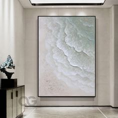 an abstract painting hangs in the corner of a room with white walls and flooring