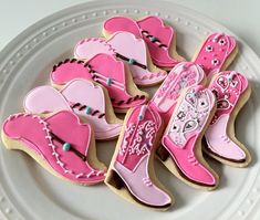 decorated cookies on a white plate with pink and blue decorations in the shape of cowboy boots