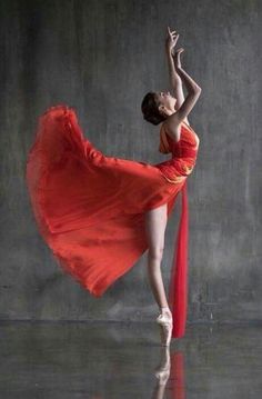 a woman in an orange dress is dancing