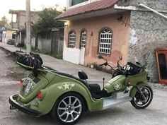 a green motorcycle parked on the side of a road next to a building with windows