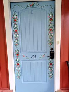 a blue front door with flowers painted on the side and numbers in red, white and blue