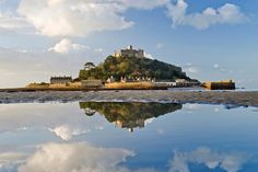 a small island with a castle on top is reflected in the water at low tide