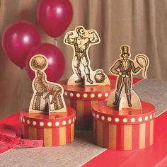 three wooden cutout figurines sitting on top of a table next to red balloons