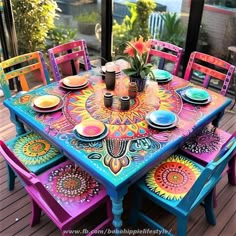 the colorful table is set with four chairs and place settings for six people to sit at