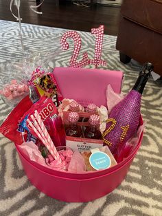 a pink basket filled with candy, candies and other items sitting on a table