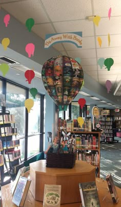 a library with balloons and books on the table in front of it is filled with children's books