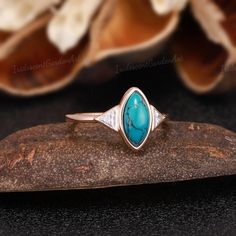 a turquoise stone ring sitting on top of a rock