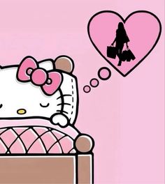 a hello kitty sitting on top of a bed next to a heart